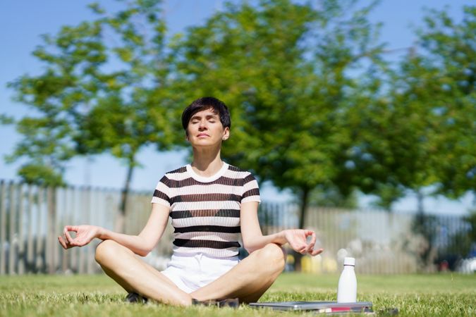 Woman meditating in grassy park