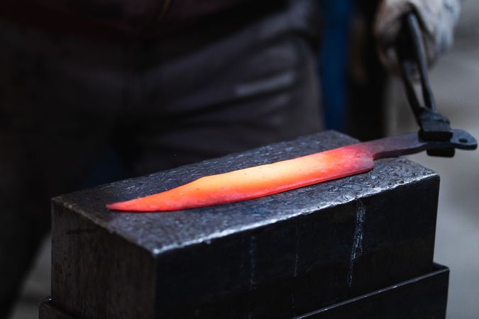 Master forging hot iron on anvil