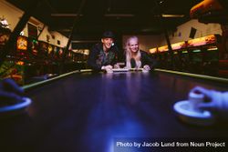 Man and woman playing a game of air hockey in the game room 4ZKErb