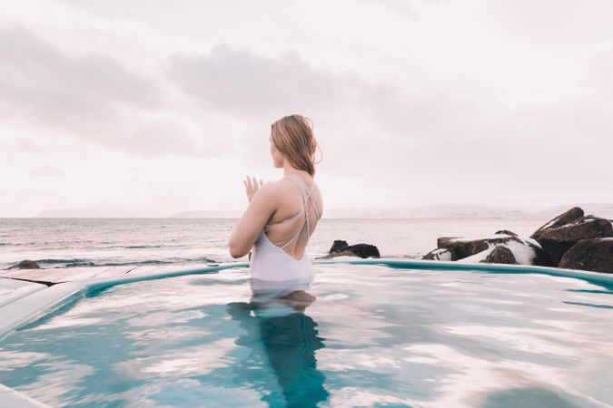 Woman sitting in pool near stones