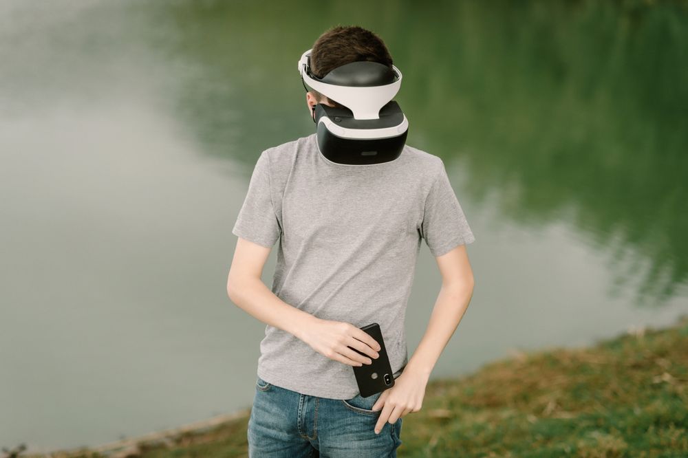 Young teenager with virtual reality glasses and smart phone outdoors