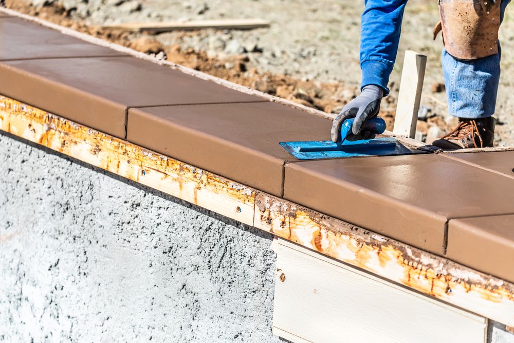 Construction Worker Using Trowel On Wet Cement Forming Coping Around New Pool