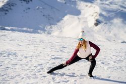 Stylish woman doing yoga exercise on snowy terrain