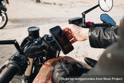 Man checking smartphone on motorcycle bYR1g0