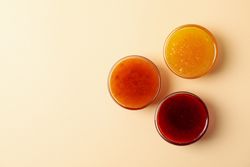 Bowls with jam on beige background, top view