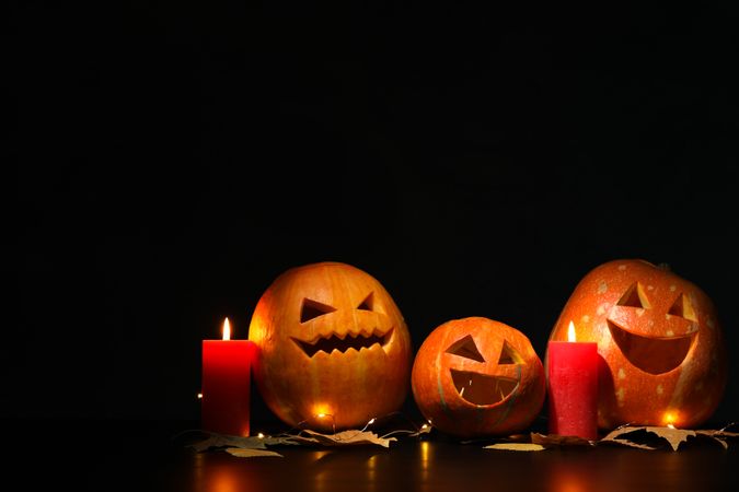 Halloween pumpkins and candles on dark background, copy space