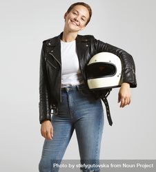 Smiling woman in dark leather jacket with light t-shirt posing with motorcycle helmet under arm 5QnzV4