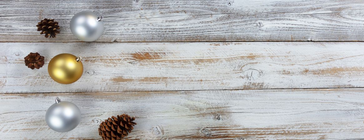 Traditional silver and gold Christmas balls with pine cones on wood
