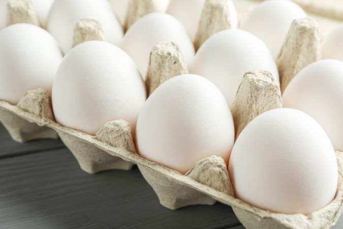 chicken eggs in carton box on wooden table, space for text and closeup