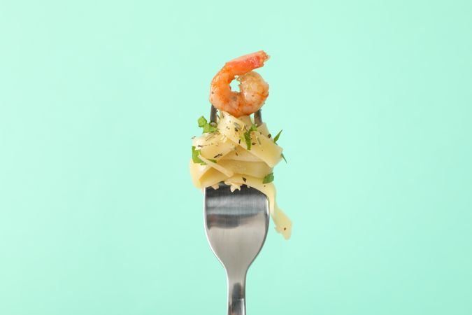 Fork with tasty pasta on mint background, close up