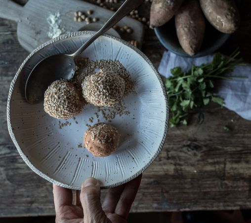 Person rolling in breadcrumbs sweet potatoes