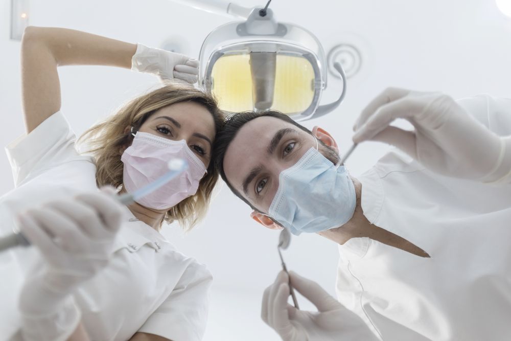 Two dentists leaned over patient in chair at clinic