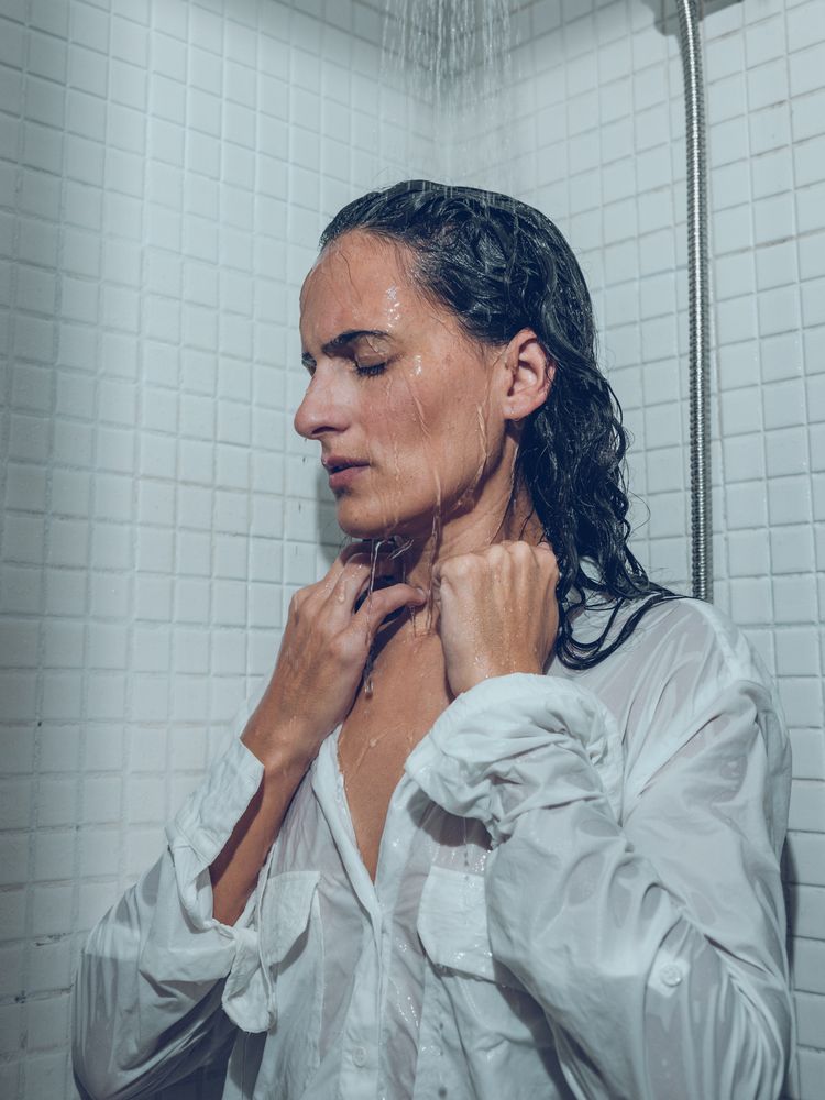 Tired woman with wet hair in shirt taking shower