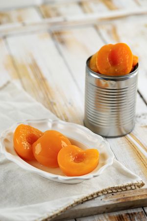 Bowl of peaches on table next to tin