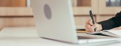 Laptop with person writing notes