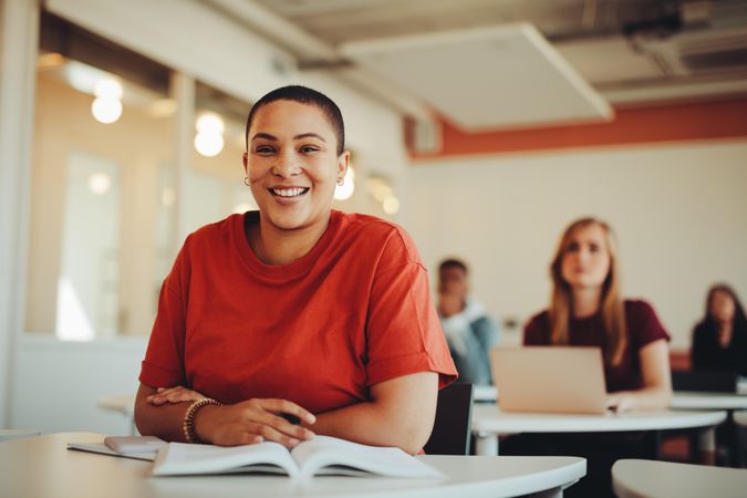 Happy female student sitting at desk and smiling at camera