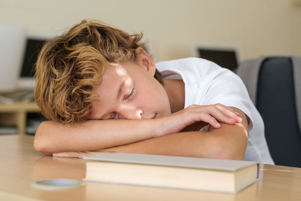 Pupil sleeping on table in classroom