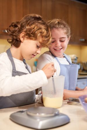 Siblings mixing ingredients for dough in container