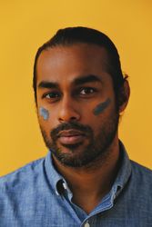 Indian male standing with mud mask on face, vertical