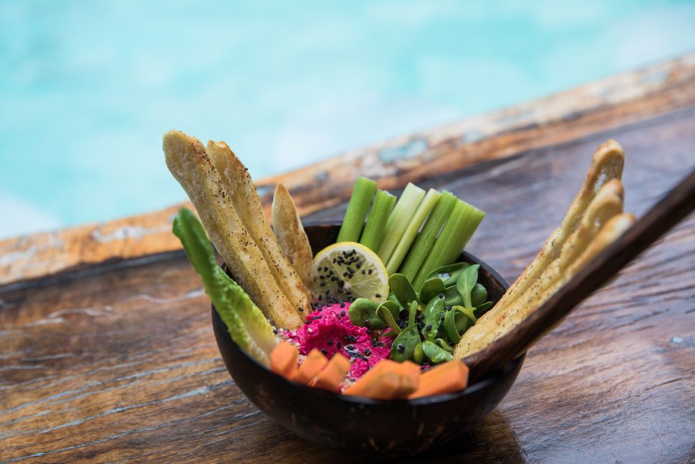 bowl of fresh vegetables and bread near glass of shake on wooden table in Mexico