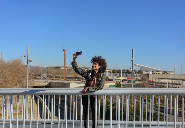 Woman with afro hair looking at her phone while walking.
