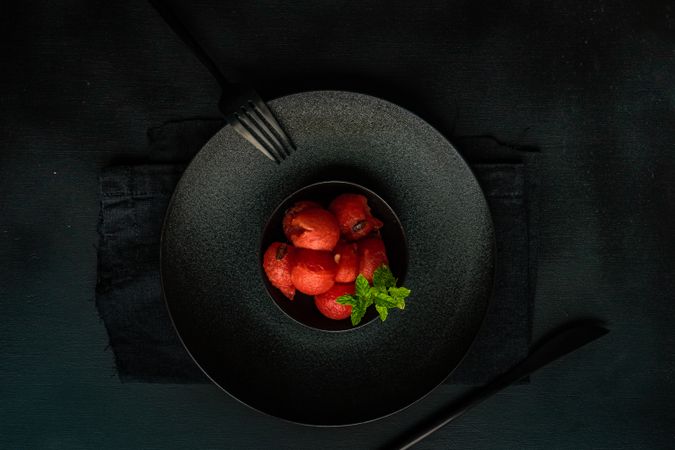 Top view of red sorbet on dark plate, served with napkin and silverware