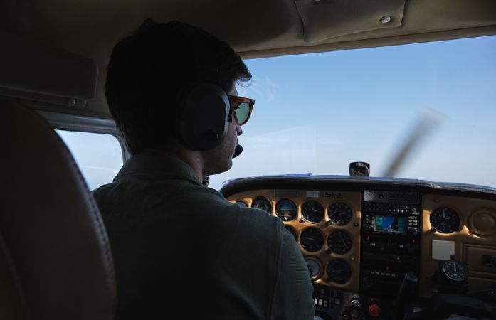 Concentrated pilot operating helicopter in blue skies