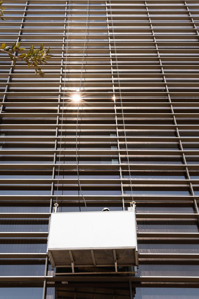 Faceless male window washer cleaning high building facade in construction