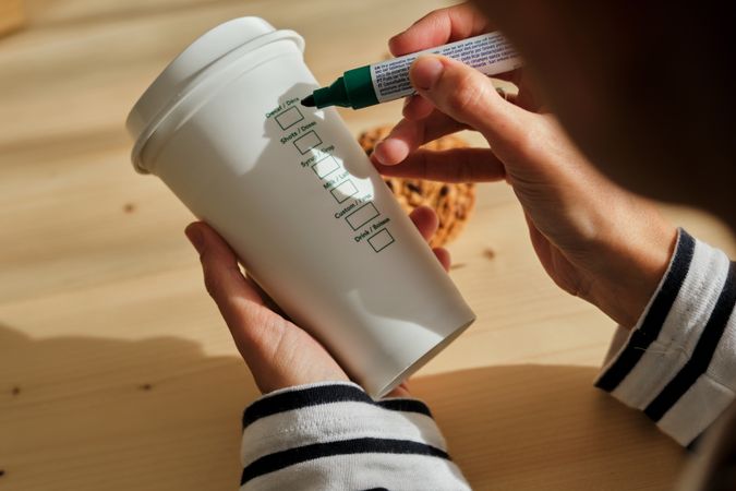 Unrecognizable woman writing at takeaway coffee cup
