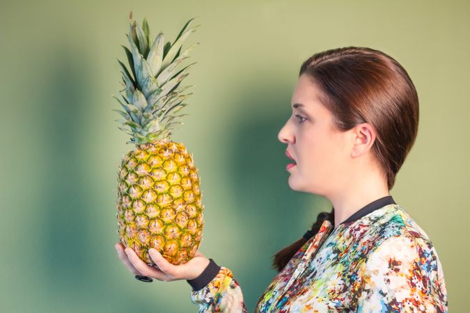 Woman looking a pineapple in her hand