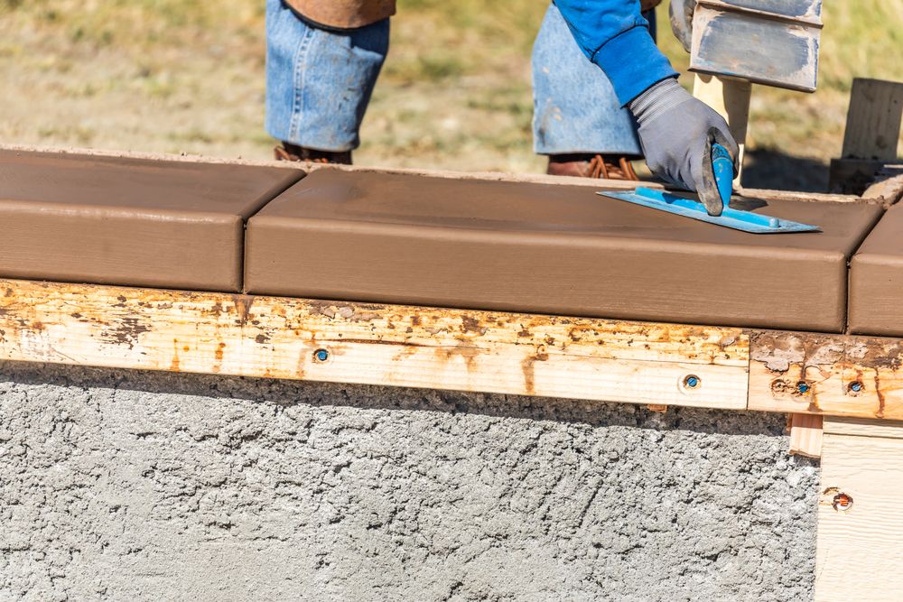Construction Worker Using Trowel On Wet Cement Forming Coping Around New Pool