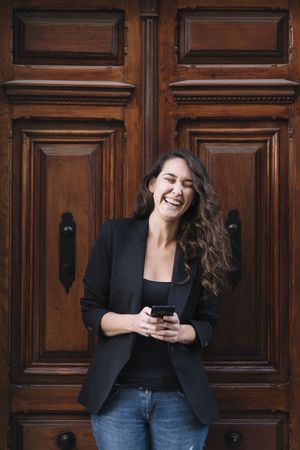 Young female using mobile phone on wooden door