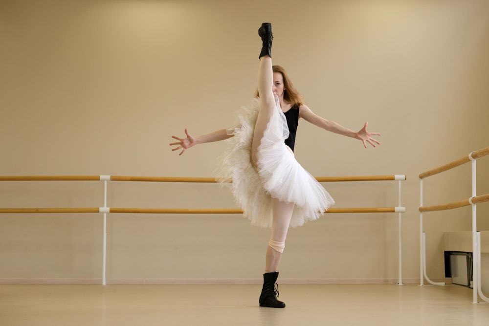 Ballerina in shoes and tutu, balancing with arms wide