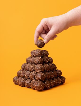 Chocolate candies stacked as a pyramid on an orange background