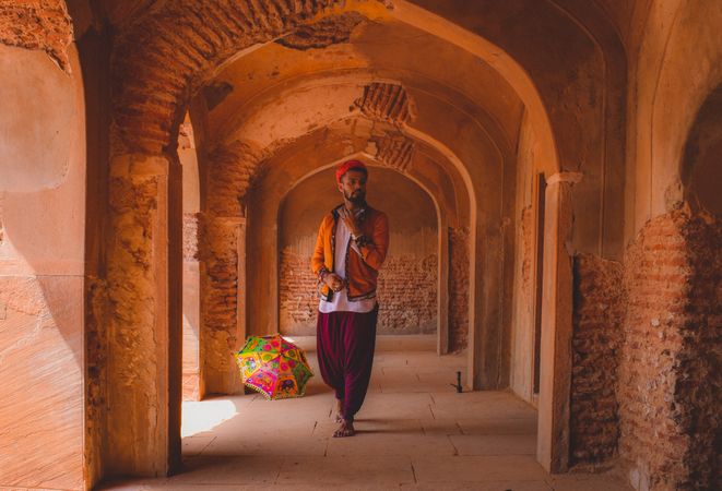 Man in traditional outfit standing in hallway of ancient building