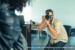 Photographer focusing his DSLR camera on a model during a photo shoot bYkoj5
