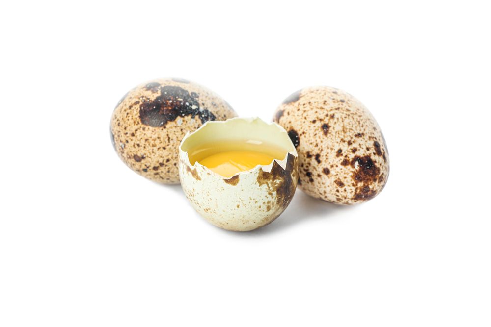 Quail eggs and half broken egg with yolk isolated on light background