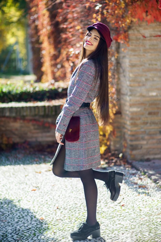Happy female in warm winter clothes standing outside on sunny day
