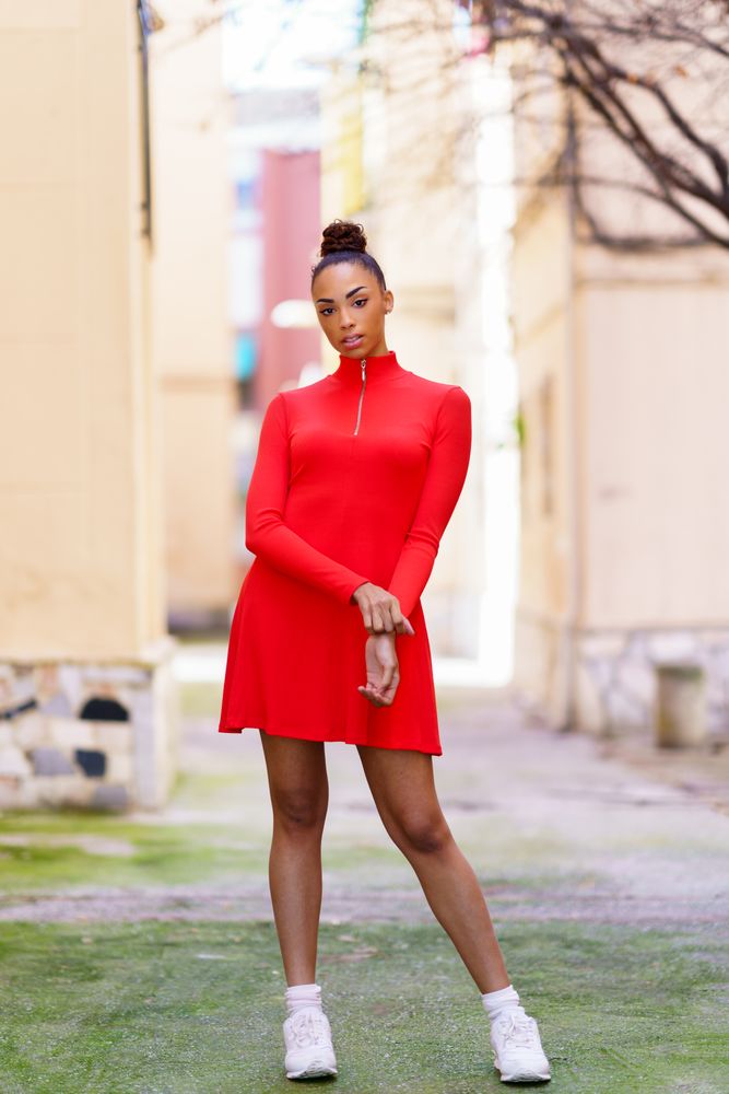 Woman in casual red dress standing in alley on sunny day