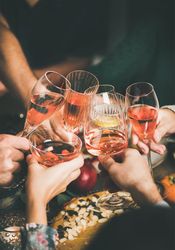 Group of people at festive fall dinner toasting with wine, water, close up