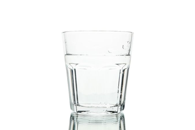 Tall glass of water with ridges in plain room