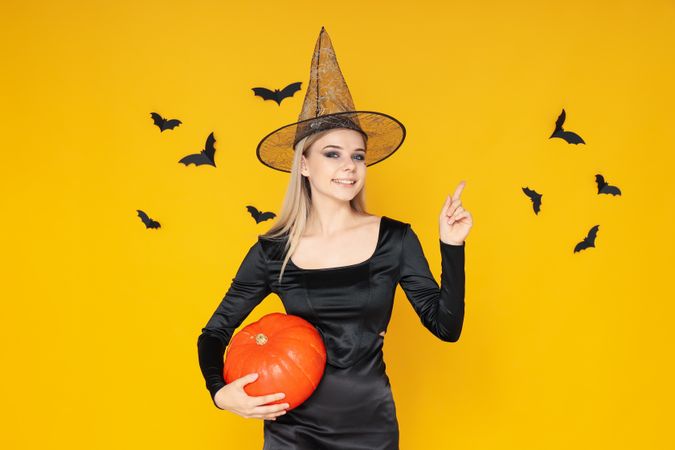 Concept of Halloween, young woman on yellow background