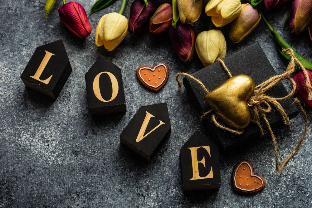 Valentine's day card concept with the word "love" on grey counter with spring flowers and heart ornaments