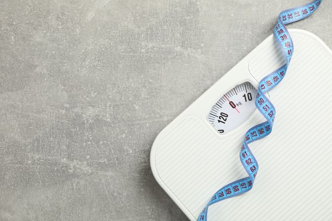 Scales and measuring tape on gray background. Weight loss concept