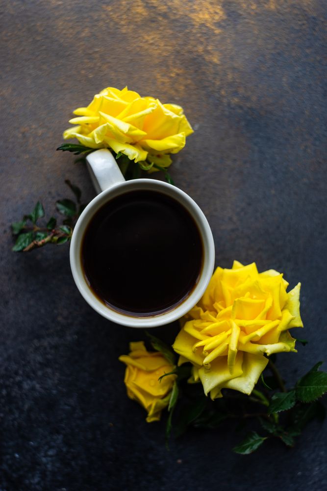 Top view of cup of coffee and yellow roses with copy space