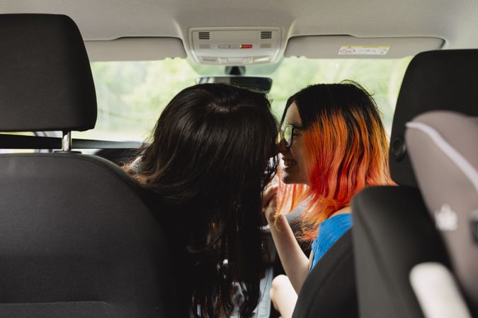 Two young lesbian women kiss inside the car during a trip
