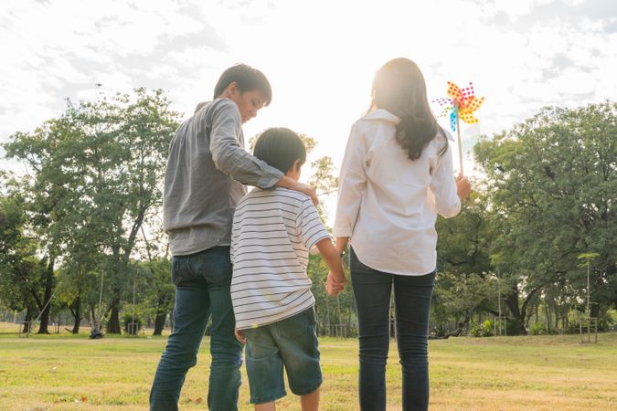 Father with arm on son’s shoulder with mother holding child's hand in park