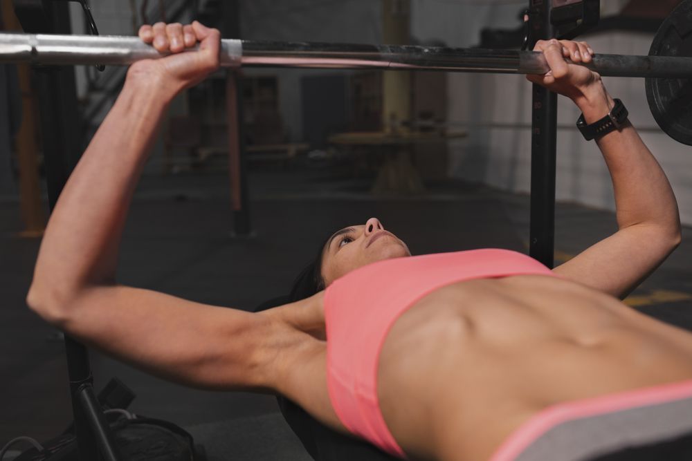 Athletic woman training with barbells in gym