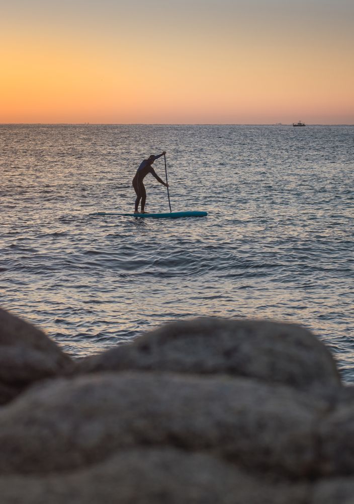 Man practicing paddle surfing with neoprene in a sunrise