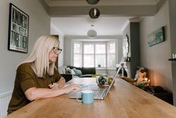 Older woman with grey hair working from home in kitchen
